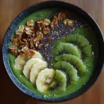 Green smoothie bowl topped with banana, kiwi, chia seeds, and granola